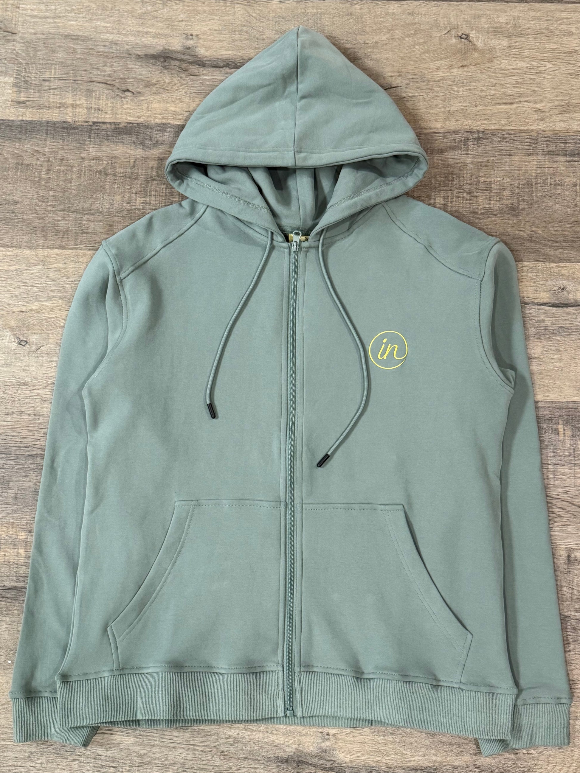 Green hoodie with a logo on a wooden surface
