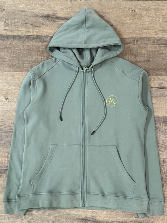 Green hoodie with a logo on a wooden surface
