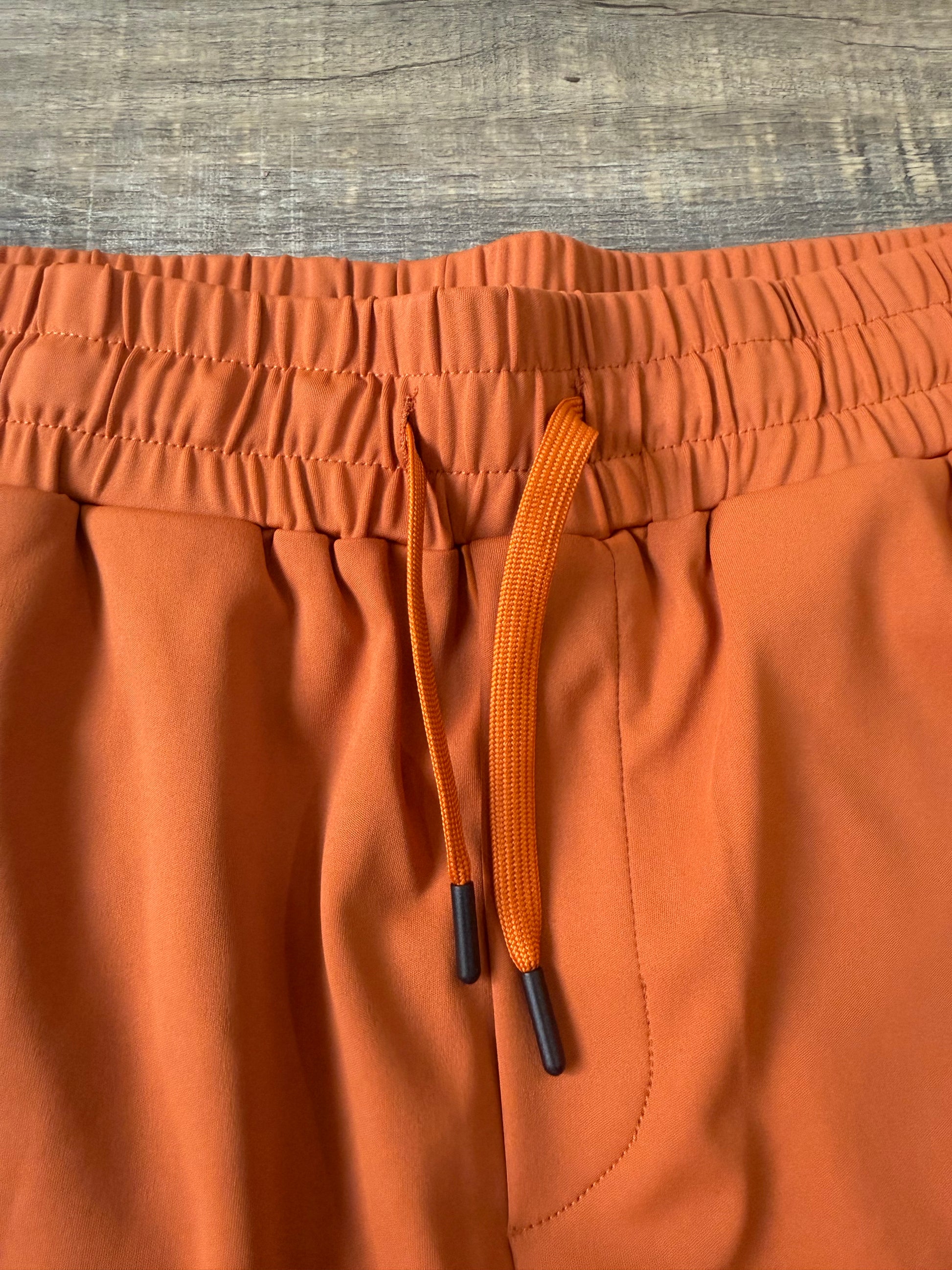 Inherit Noir Relaxed Fit Signature Joggers in Orange. Flat-lay product detail.