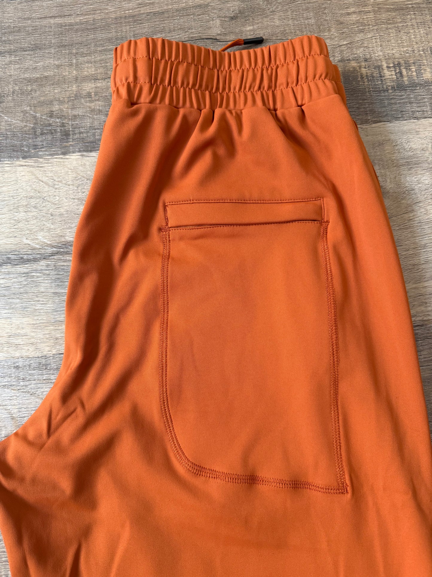 Inherit Noir Relaxed Fit Signature Joggers in Orange. Flat-lay product detail.